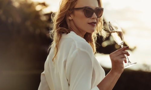 a woman sipping on wine outdoors in a bright dress